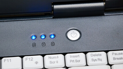 Laptop power button up close, powering on, turning on an electronic device, computer startup concept, closeup, symbol detail. Appliance turning on, led lights coming on indicators blinking, nobody