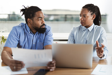 African American business couple working on a computer in the office. Focus is on woman