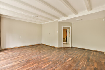 an empty living room with hardwood flooring and white painted ceiling beams on the ceiling is not visible in this photo