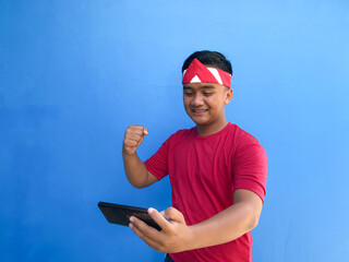 Beautiful Asian man giving salute celebrate Indonesian independence day on August 17 using red...