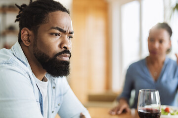 Close up of young African American man feeling sad while arguing with his wife at dining table