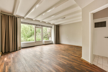 Obraz premium an empty living room with wood flooring and large windows looking out onto the trees in the woods behind it