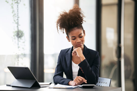 African american businesswoman in suit using calculator to calcu
