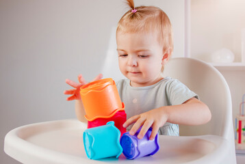 Little child plays with colorful plastic toys pyramid at home. Baby game. Games for early development
