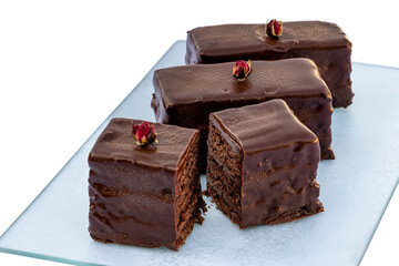 Three pieces of chocolate biscuits on glass board. One piece is сut and the cut is visible. 