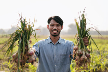 Smart farmer holding garlics in both hands and happiness with ex