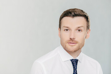 Attractive male freelancer works remotely, wears elegant white shirt with tie. Isolated on white studio wall. People, facial expressions, and work concept.