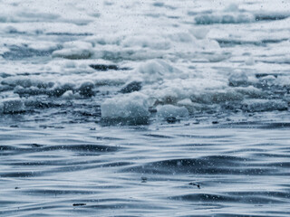 Photography of ice on arctic ocean. Drift and brash ice forming and floating on the surface of the northern sea. Gloomy weather, grey, white, blue colors, cold tone