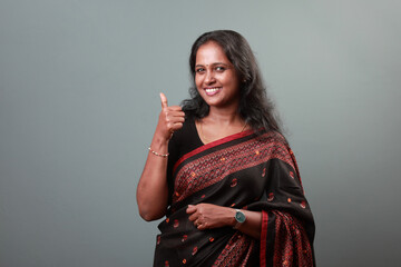 Portrait of a woman of Indian origin wearing traditional dress Sari with a thumbs up hand gesture