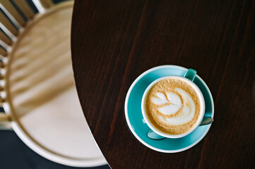 Coffee cappuccino in cup on wooden table in cafe