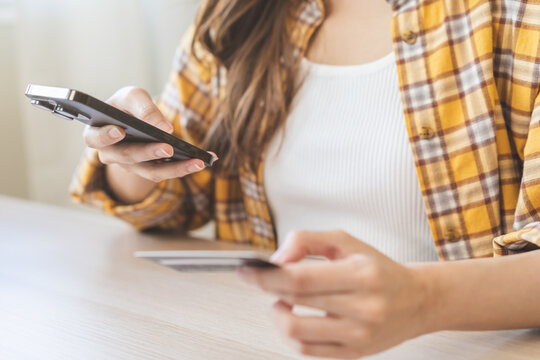 Bill Pay, Shopping Order Online Internet Asian Young Woman Hand Holding Credit Card And Mobile Smart Phone On Desk At Home, Female Using Banking Service To Secure Payment With Purchase On Store.