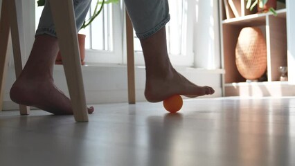 Man using silicone ball for foot massage under table during long sedentary work. Physical exercises for feet recovery after trauma injury, improving blood circulation, prevention of leg diseases. - Powered by Adobe