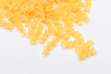 A Heap of Uncooked Fusilli Pasta Scattered on White Table. Raw and Dry Macaroni. Unhealthy and Fat Food. Italian Culture
