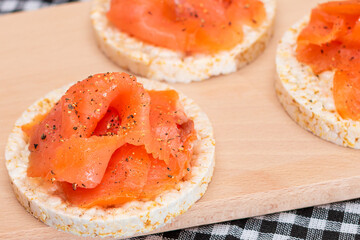 Tasty Rice Cake Sandwiches with Fresh Salmon Slices on Wooden Cutting Board. Easy Breakfast and Diet Food. Crispbread with Red Fish. Healthy Dietary Snack