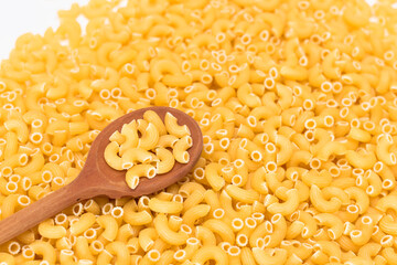 Uncooked Chifferi Rigati Pasta Background with Wooden Spoon. Fat and Unhealthy Food. Classic Dry Macaroni. Italian Culture and Cuisine. Raw Pasta