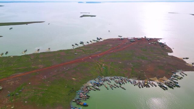 Aerial view of Ben Nom fishing village, a brilliant, fresh, green image of the green algae season on Tri An lake, with many traditional fishing boats anchored.