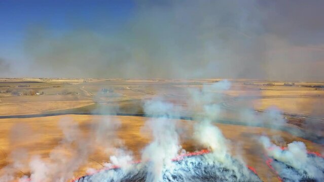 Aerial Backward Shot Of Smoke Emitting From Fire On Field During Sunny Day - Billings, Montana