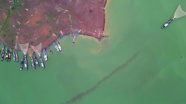 Aerial view of Ben Nom fishing village, a brilliant, fresh, green image of the green algae season on Tri An lake, with many traditional fishing boats anchored.