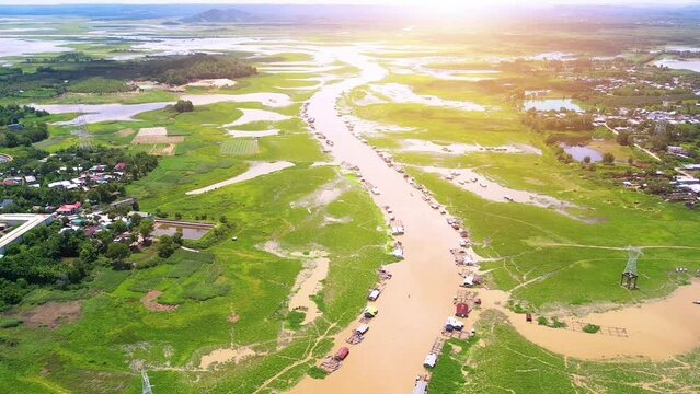 Aerial view of National Route 20 in Dong Nai province, group of floating house on La Nga river, Vietnam with hilly landscape and sparse population around the roads.