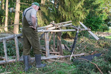 An elderly hunter looks at the damage the storm has done to his hunting pulpit, which has just been...