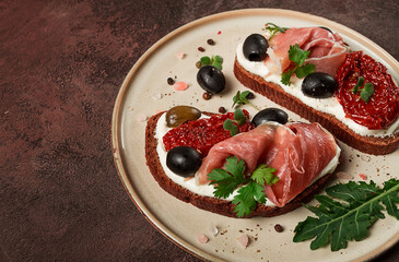 sandwiches with cheese and prosciutto, dried tomatoes and olives, breakfast on a plate,