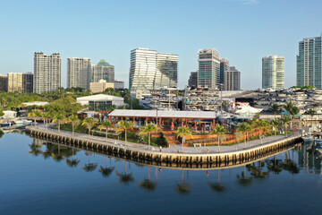 Obraz premium Aerial view of waterfront bars, restaurants and marina in Coconut Grove, Miami, Florida with skyline in background on calm clear sunny summer morning.