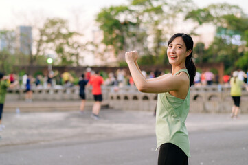 Female jogger. Fit young Asian woman with green sportswear aerobics dance exercise in park and enjoying a healthy outdoor. Fitness runner girl in public park. Wellness being concept