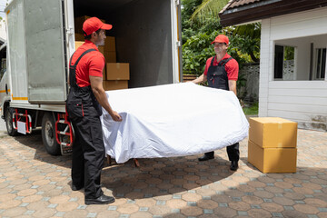Portrait of two movers unloading boxes and furniture from a pickup truck.
