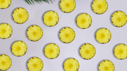 Creative summer pattern made of pineapple rings and tropical leaf against pastel pink background. Original pineapple decoration. Creative summer idea. Fruit art. Copy space. Seamless pattern.