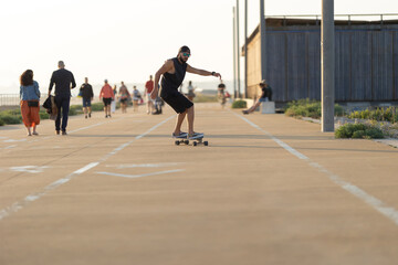 Fototapeta premium Adult attractive man in black clothes skating on the street