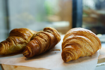 close-up photo of croissant bread yummy brown There are 3 wares in the café, ready for customers to come in and order.