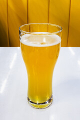 Glass goblet with light beer on a white table close-up