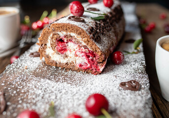 Chocolate cake with cherries and cream on wooden background. Black forest cherry swiss roll