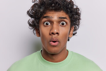 Headshot of curly Hindu man stares with terror has bugged eyes widely opened mouth dressed in...