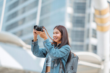 Happy young tourist asian woman holding a mirrorless camera on street in the city, Tourist journey...