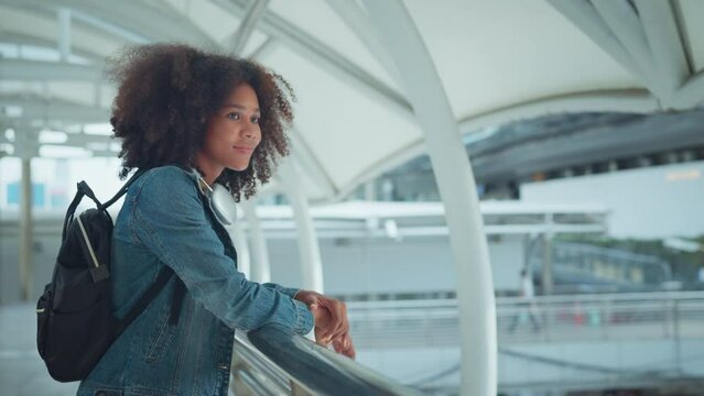 Young tourist African American woman with backpack looking at the Bangkok city while stand in train station.