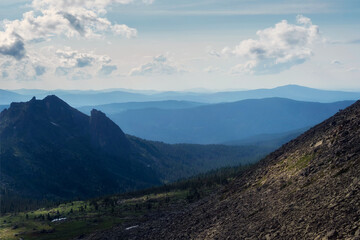 Silhouette of the Western Sayan Mountains. Foggy layered mountain landscape. Vivid sunset or sunrise scenery with low clouds in mountain valley in soft color.