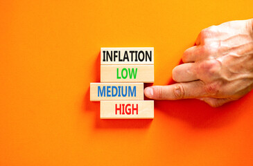 Medium inflation symbol. Concept word Inflation low medium high on wooden block. Businessman hand. Beautiful orange table orange background. Business time to medium inflation concept. Copy space.
