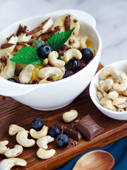 Banana salad with chocolate and cashew nuts in yogurt in a white plate. View from above. Healthy nutritious breakfast.