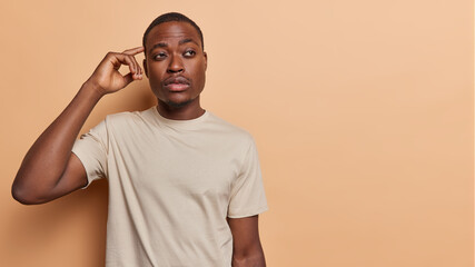 Pensive African man furrows his brow while pondering perplexing issue lost in his own thoughts...