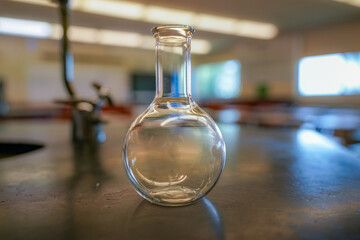 flask on a black resin table with a high school science room background.