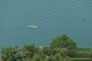 Aerial view of Lake Lugano, Switzerland, with two women using a stand up paddle