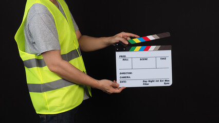 Man wear safety Vest and holding clapper board on black background.