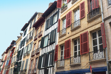 Fototapeta na wymiar In Bayonne, in the Basque country, traditional buildings with balcony windows equipped with multicolored shutters and sometimes embellished with wooden half-timbering