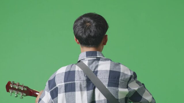 Close Up Back View Of Young Asian Teen Boy Playing Guitar With Rock Music On The Green Screen Background
