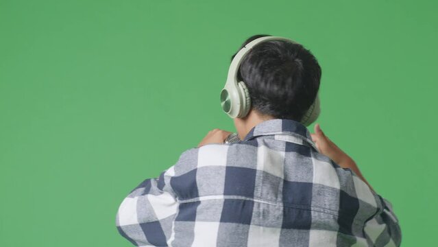 Close Up Back View Of Young Asian Teen Boy Holding A Microphone And Rapping On The The Green Screen Background
