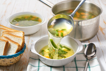 pouring vegetarian green bean soup with vegetables into a plate.