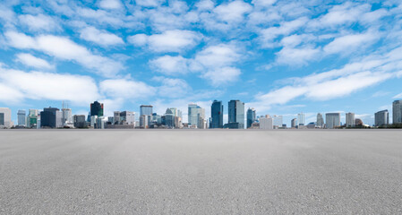 Empty wide asphalt road and city skyline. Side asphalt tarmac floor with buildings and modern cityscape, white clouds and blue sky background, highway for transportation, cloudy sky, high angle view