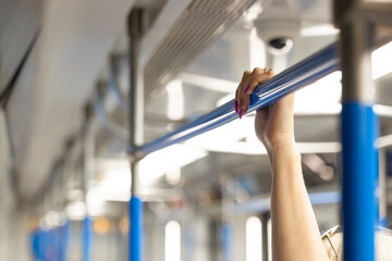 Woman holding hand on handrail in subway car
