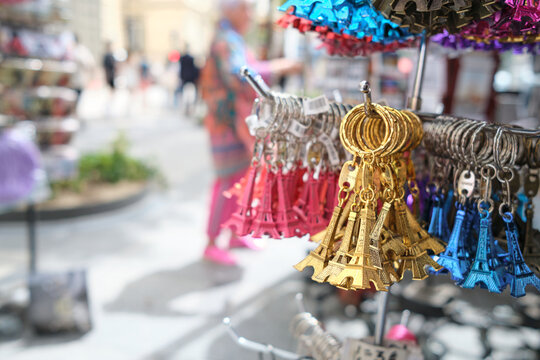 Parisian souvenirs key chains in the form of the Eiffel Tower, bundles of golden, blue and red pieces hang in a street store